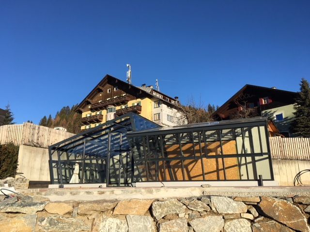 Modernes Haus mit gläsernem Wintergarten, Außentreppe und Dachterrasse.