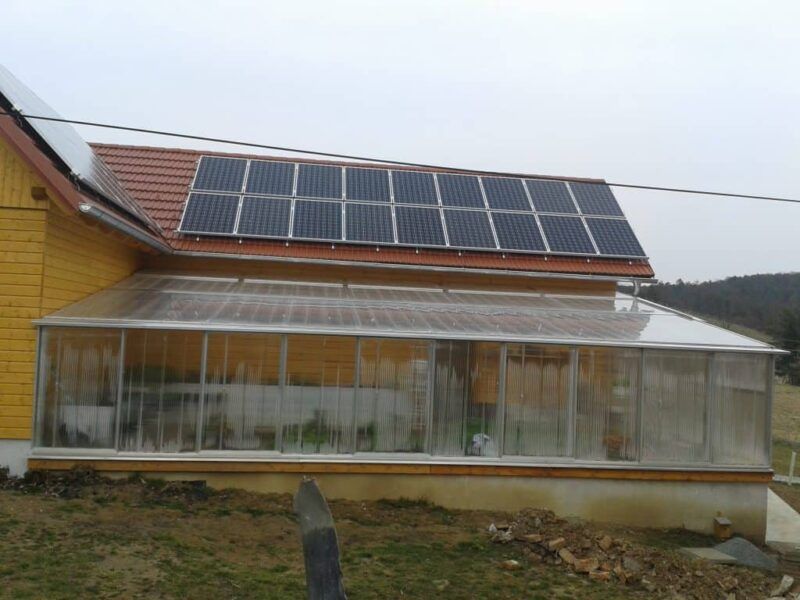 Gelbes Haus mit verglaster Veranda; Solarpaneele auf dem Dach.