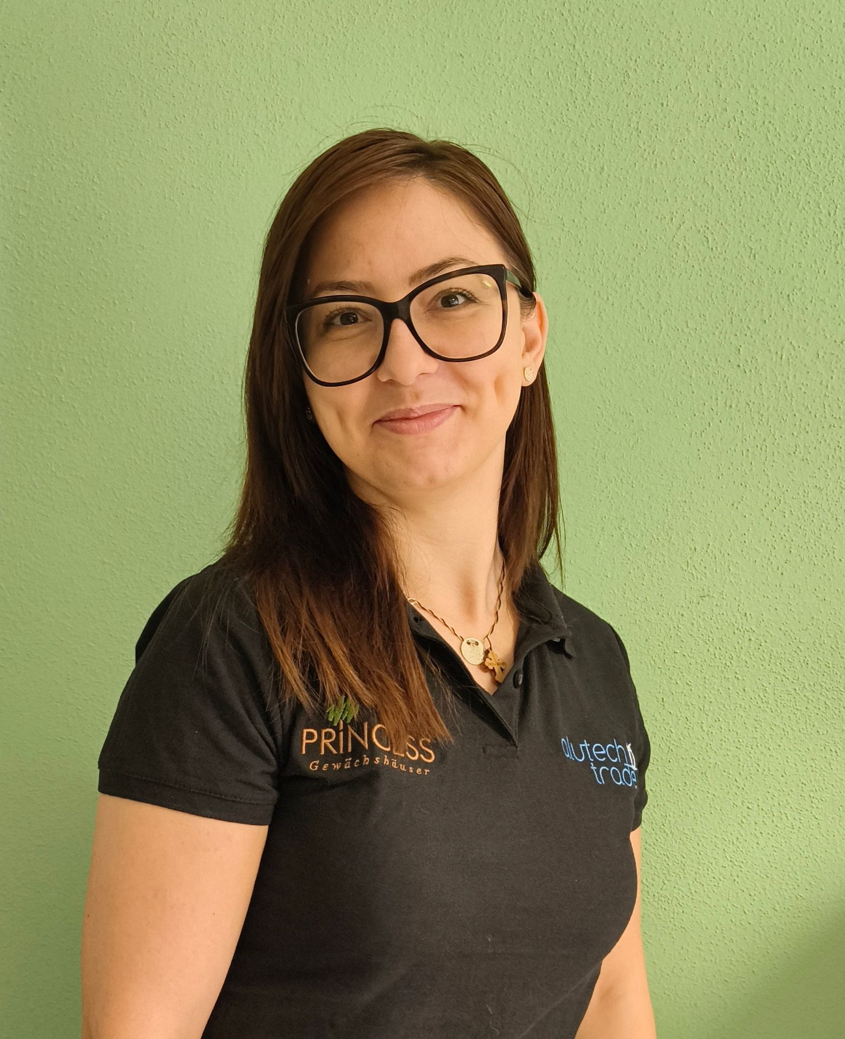 Frau mit blonden Haaren, die ein schwarzes Poloshirt trägt, lächelt in die Kamera.