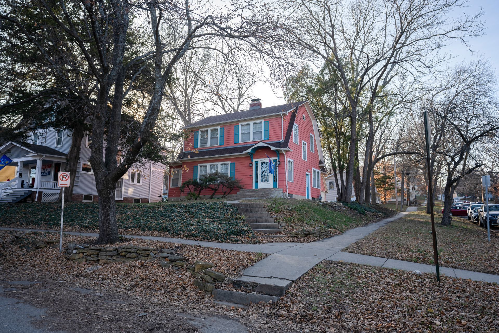 Pink house with teal shutters sits on a slight hill with a walkway in front.