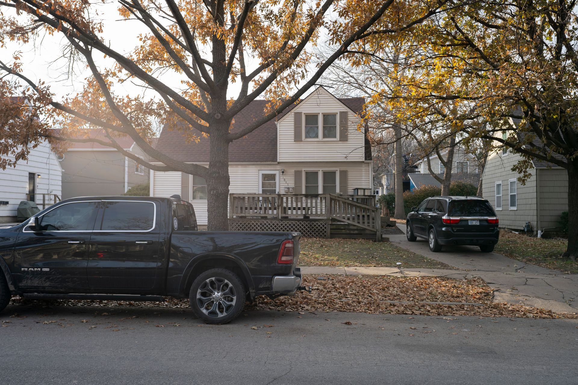 A black truck and SUV parked on a street in front of a house with a ramp.
