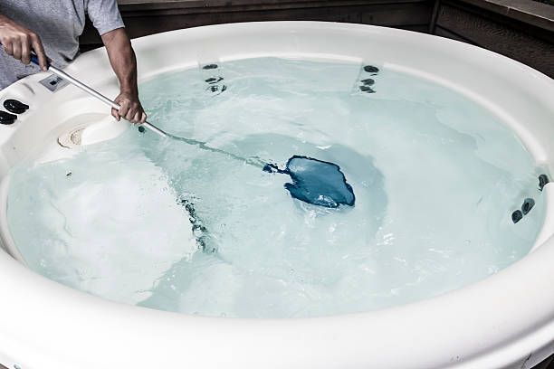 A Man Is Cleaning A Hot Tub With A Net — Aiken, NC — Aiken Junkmaster