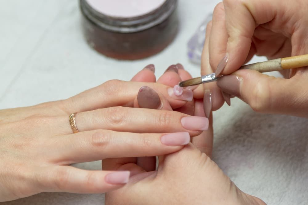 A Woman Is Getting Her Nails Painted by A Nail Artist — Villa Nails & Beauty in Cannonvale, QLD