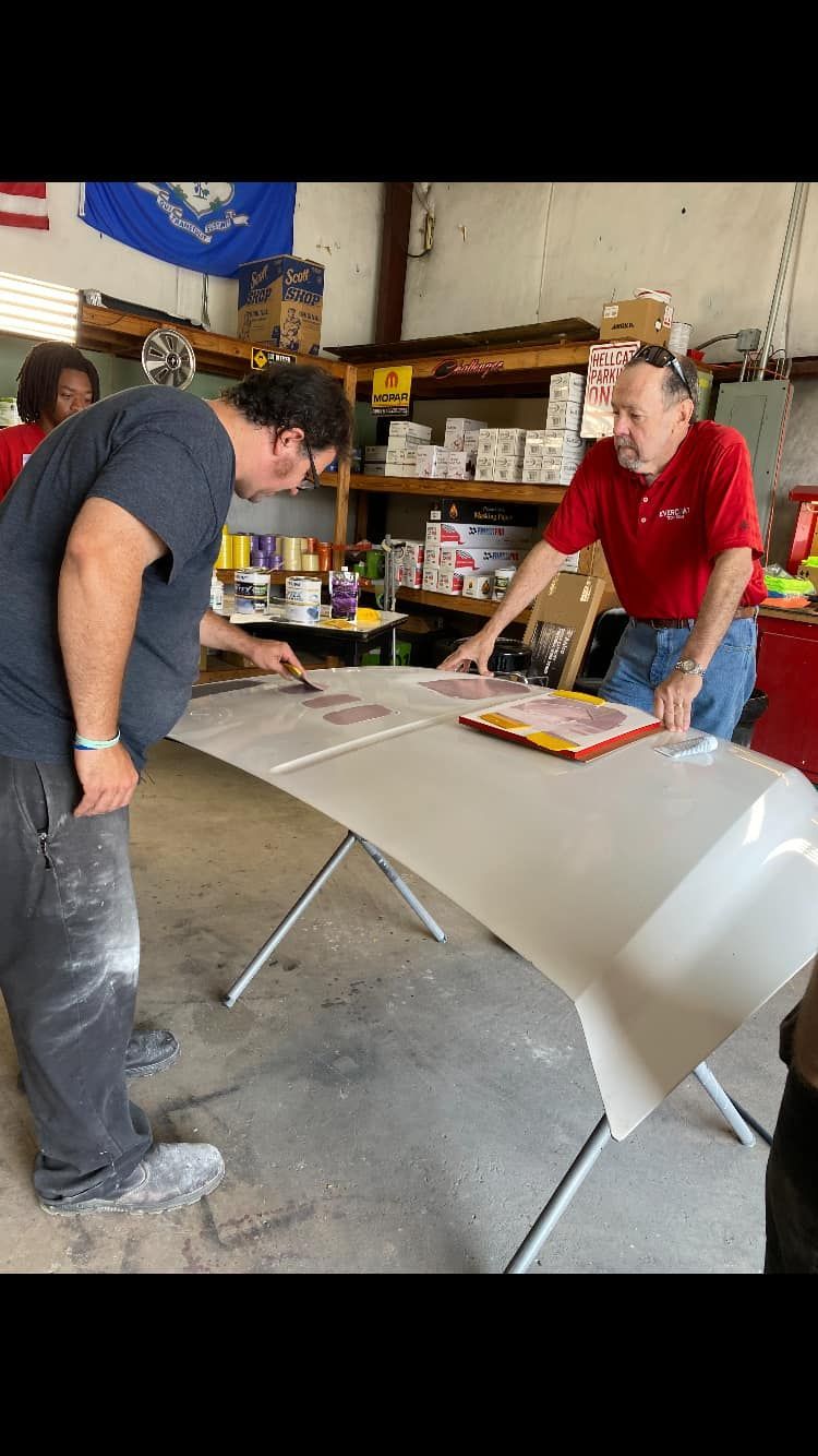 Woman in straw hat smiles, holding wine glass near a lake.