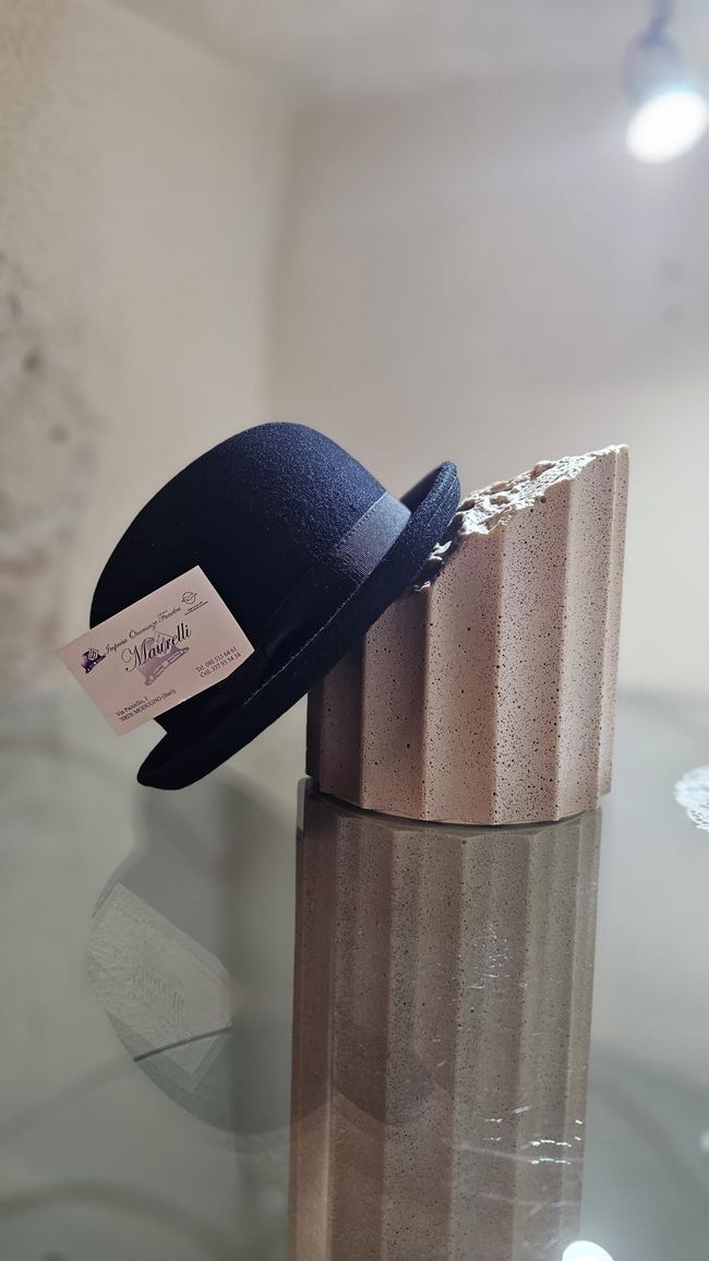 Mani appoggiate su una bara di legno adornata con una grande composizione di fiori rosa e viola.