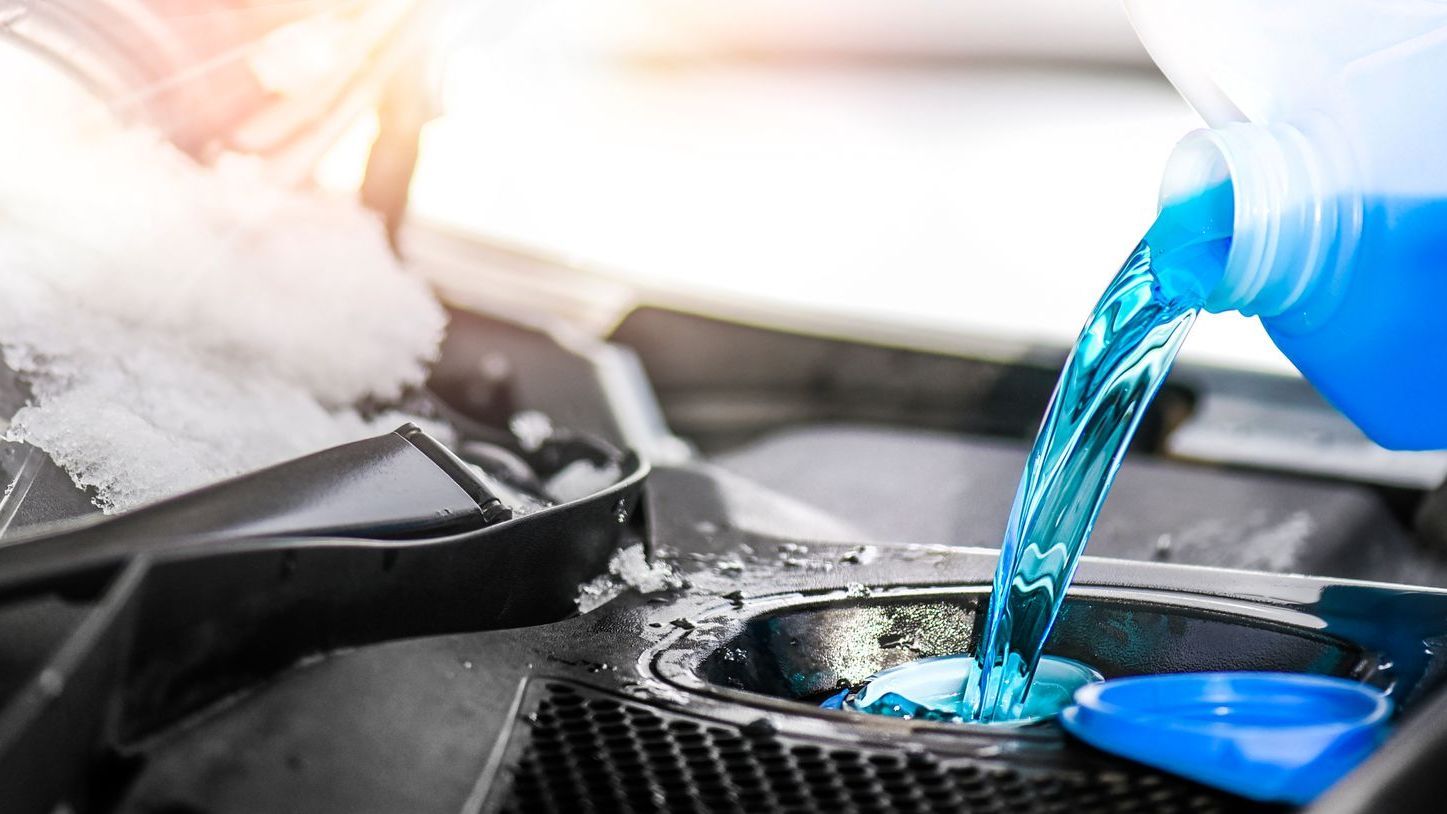 Blue screenwash being poured into a vehicle's screen wash reservoir