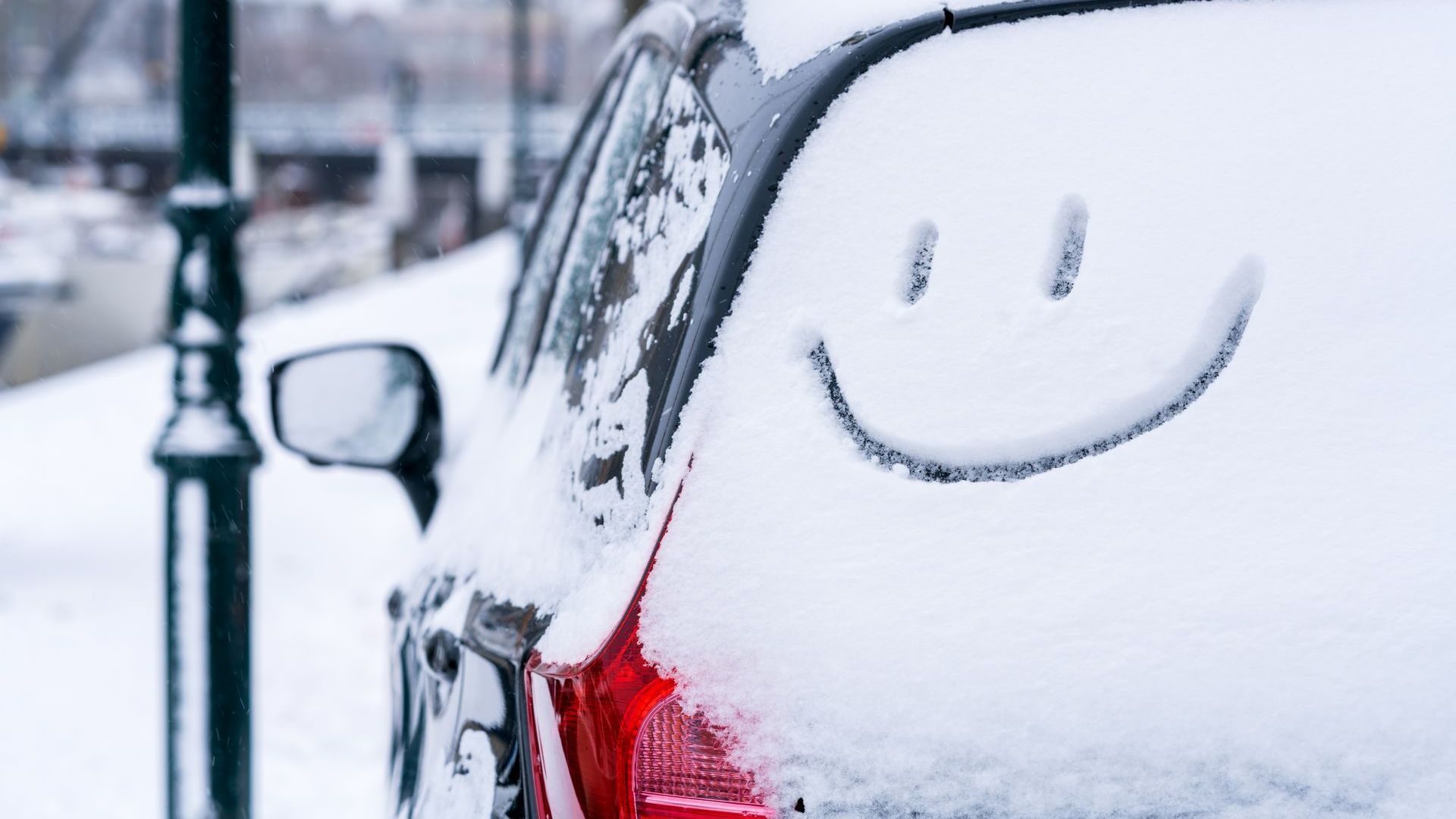 Snowy car with a smiley face drawn into the snow 