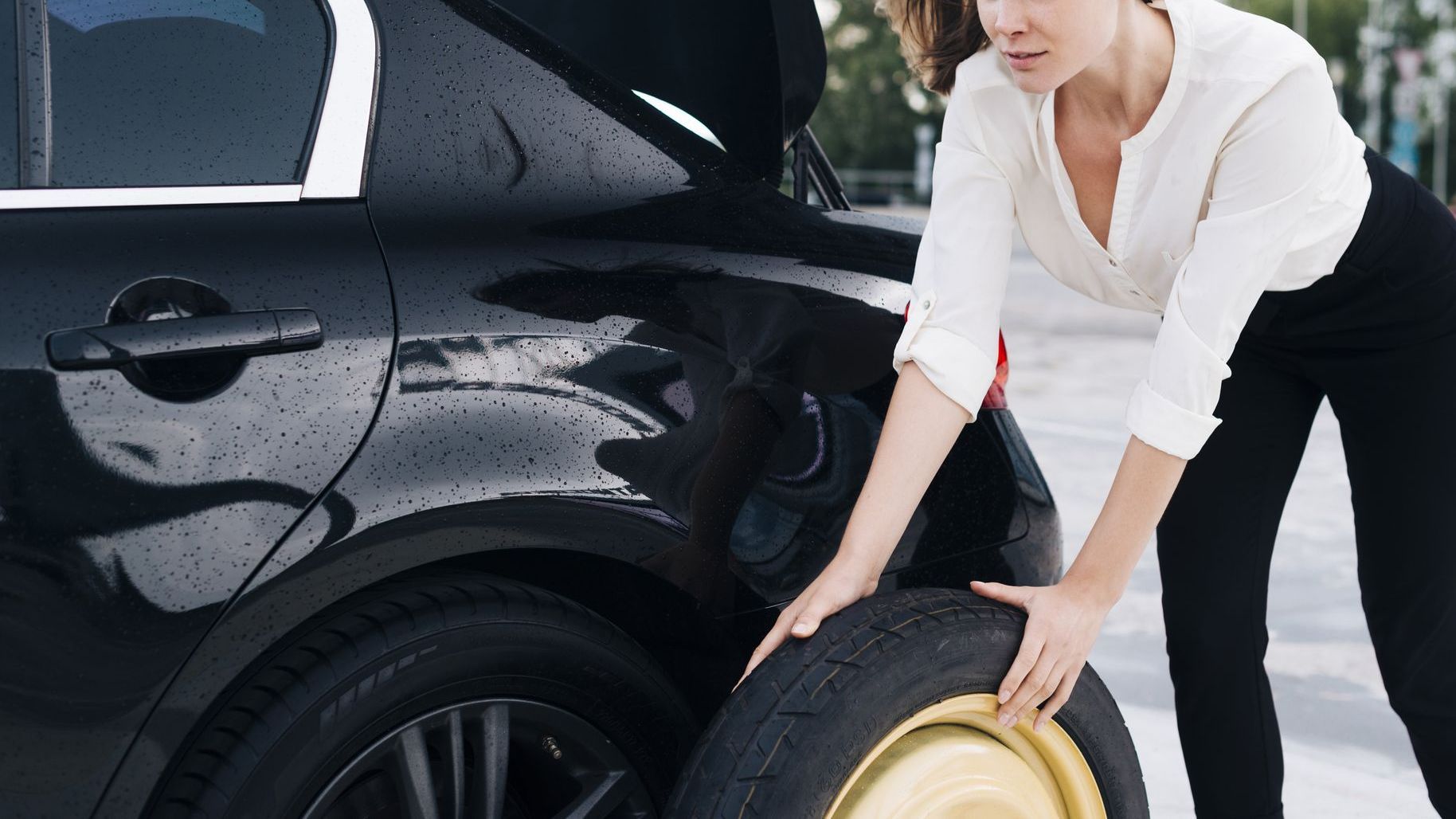 Woman changing spare tyre on a car