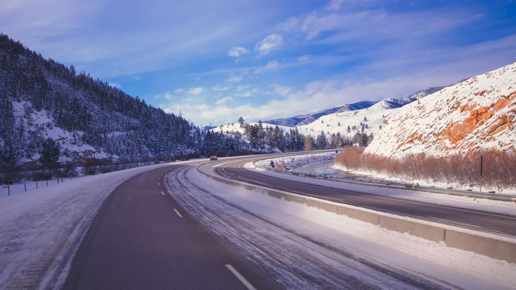 Snowy landscape with icy roads, hills, and forests. 