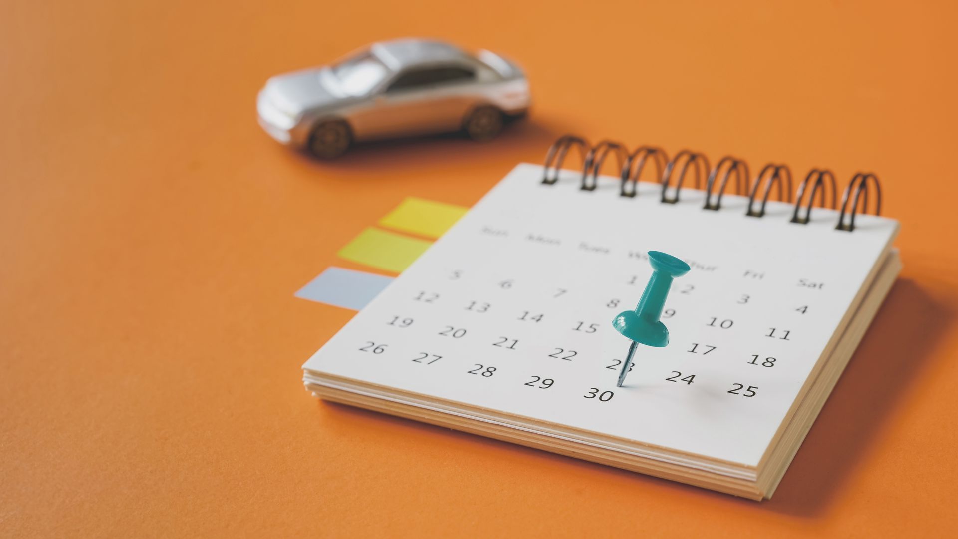 desk calendar with a pin in a date and a toy car in background