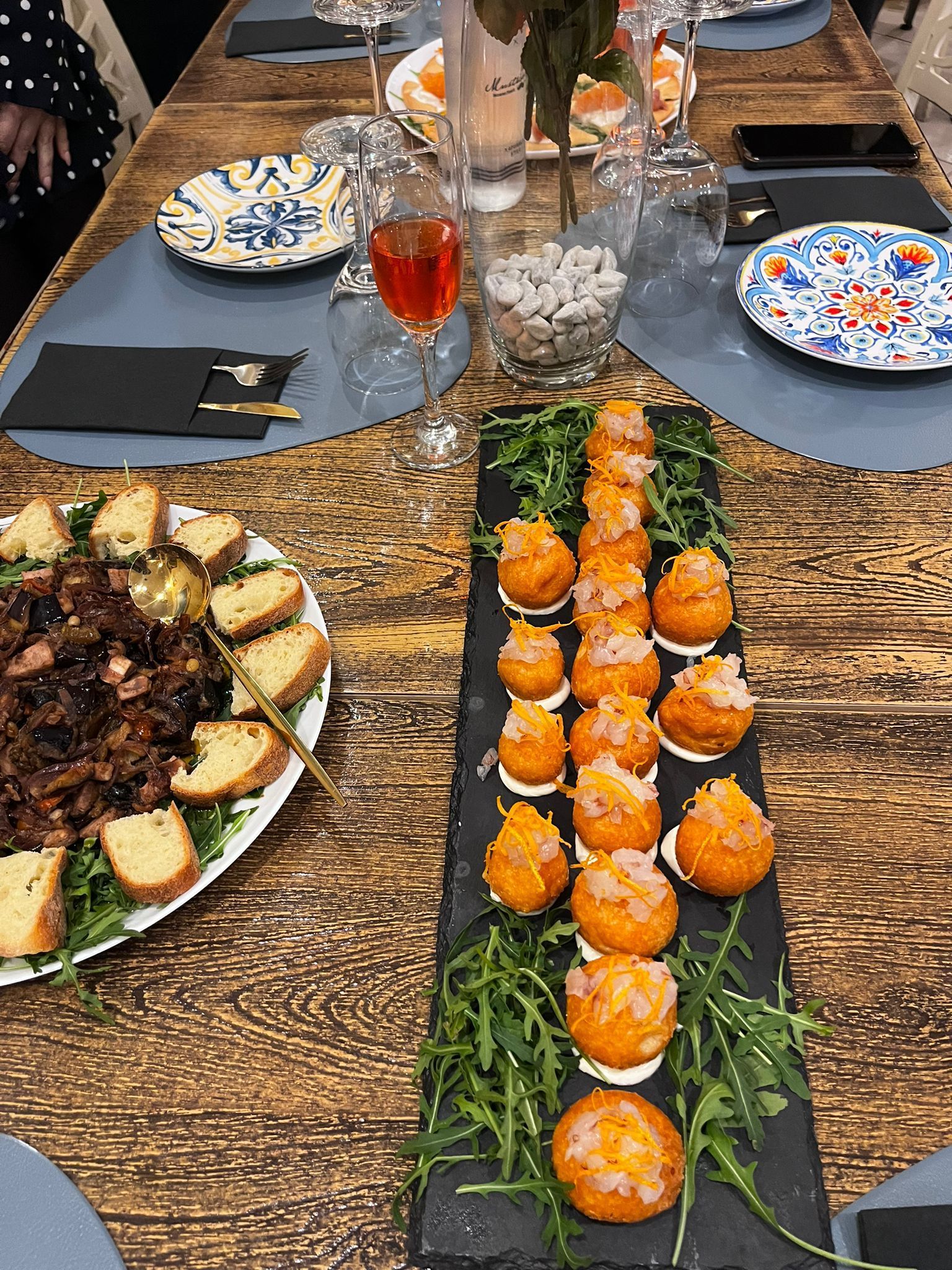 Un tavolo di legno sul quale sono disposti piatti di cibo e bicchieri di vino.