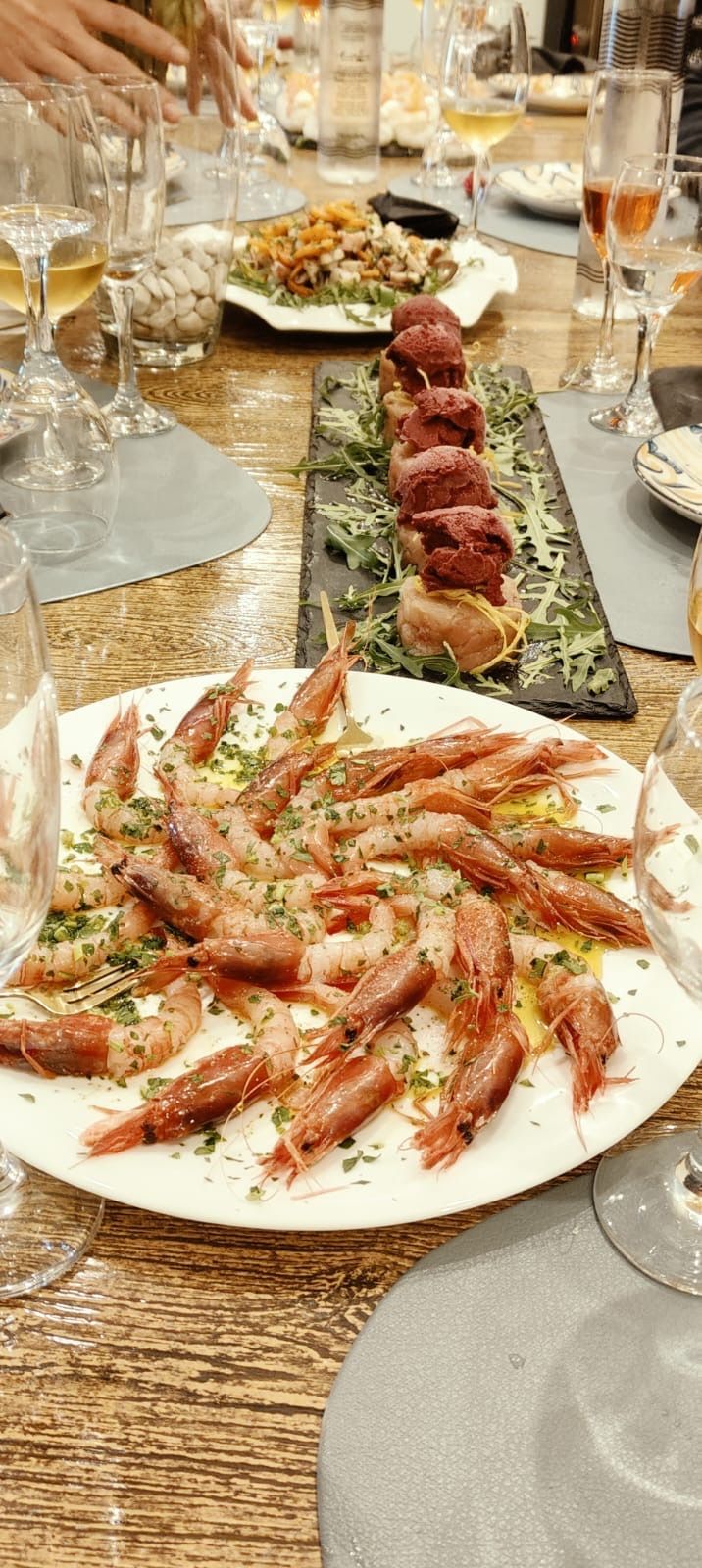 Un piatto di gamberi è appoggiato su un tavolo di legno.