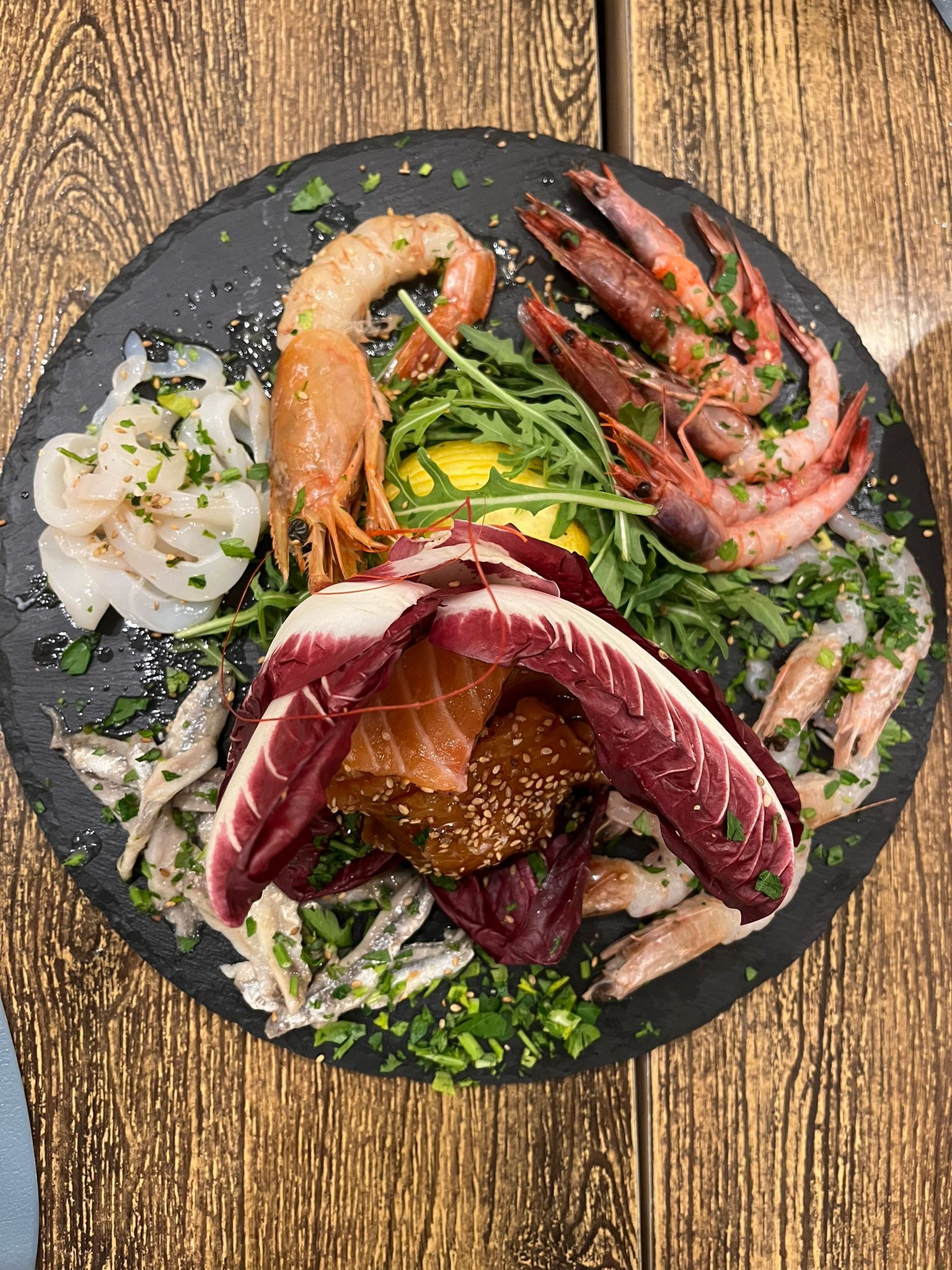 Un piatto di frutti di mare è appoggiato su un tavolo di legno.