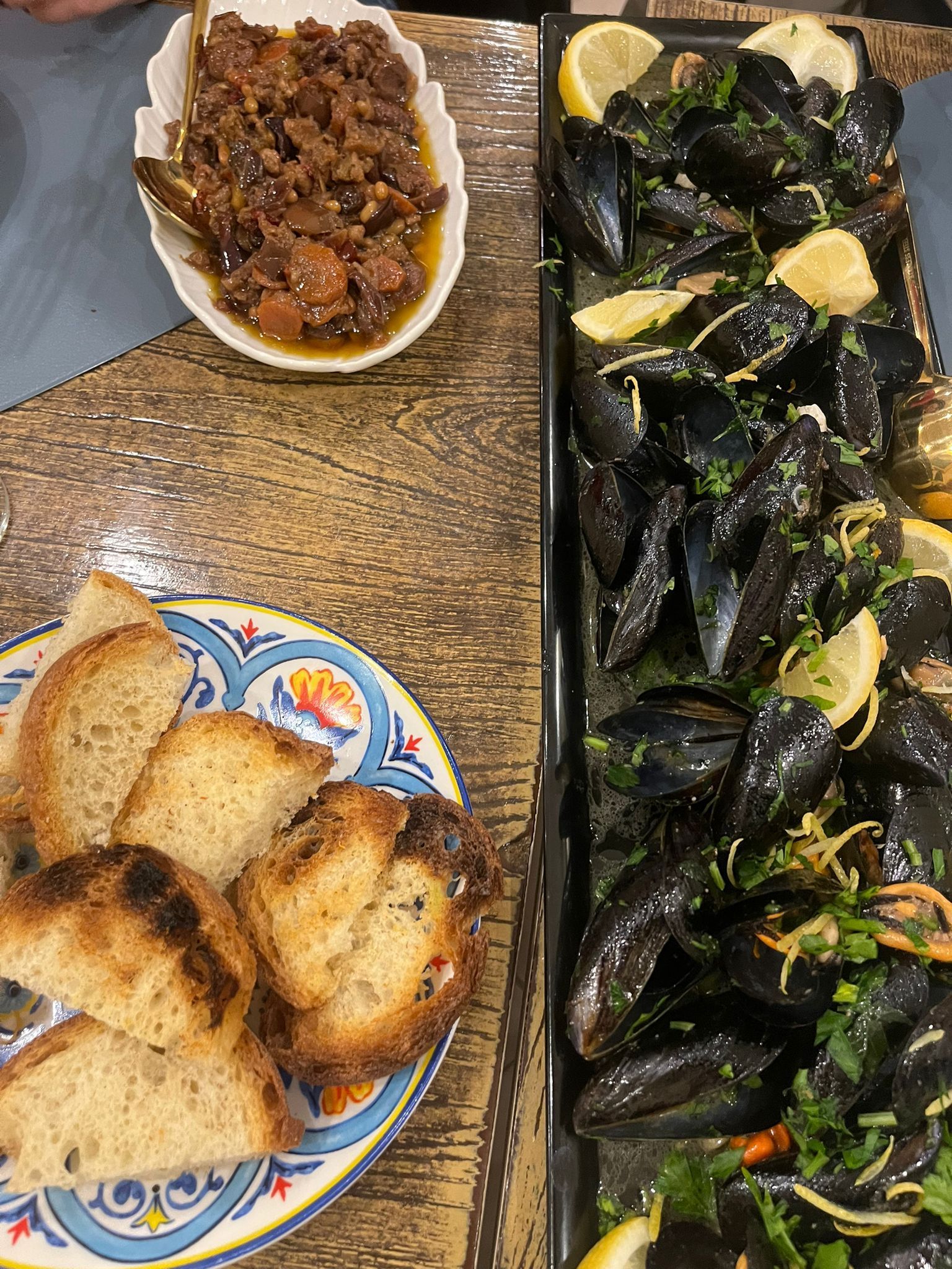 Un piatto di pane e un vassoio di cozze sono su un tavolo.