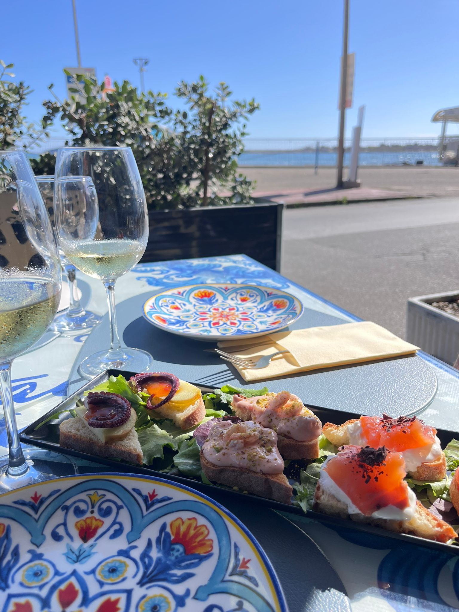 Un tavolo sormontato da piatti di cibo e bicchieri di vino.