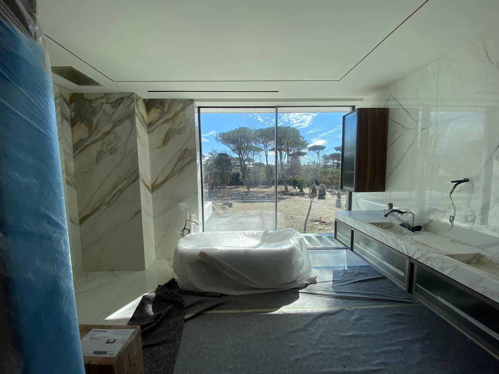 Bagno con pareti in marmo e una grande finestra con vista sul paesaggio, una vasca e un doppio lavabo.