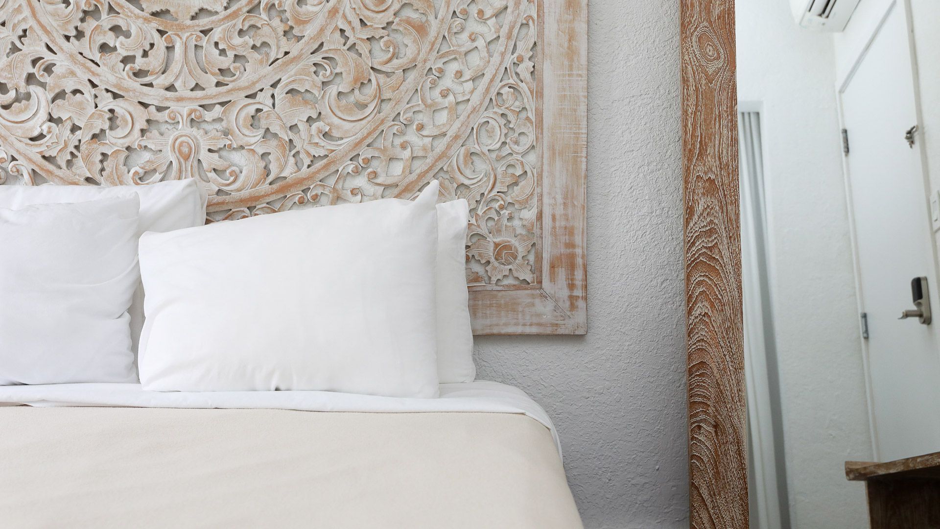 Bedroom interior with a bed, textured headboard, white linens, and a door.
