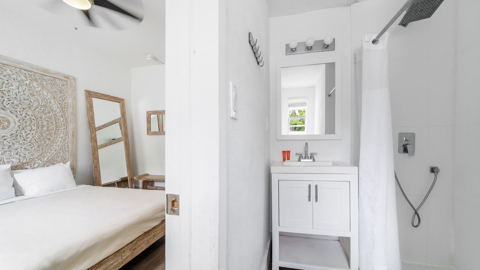 Bedroom with white bed, carved headboard, and attached bathroom with shower and vanity.