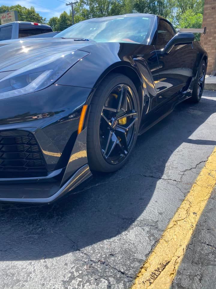 A black Chevrolet Corvette C7 Z06 parked in a sunny asphalt lot.