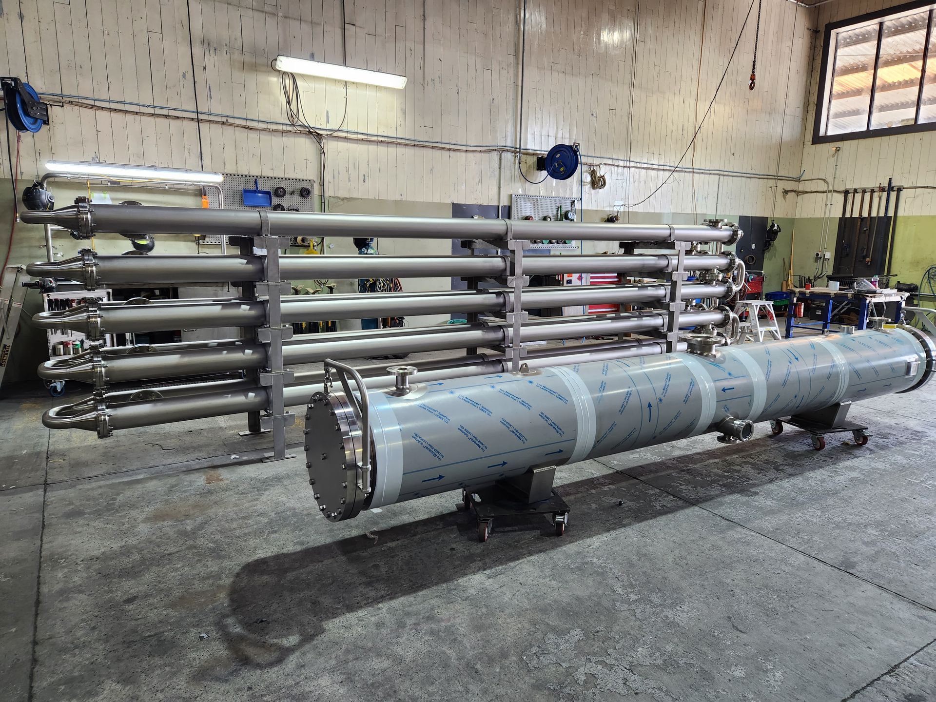Stainless steel industrial water filtration system, in a workshop setting.