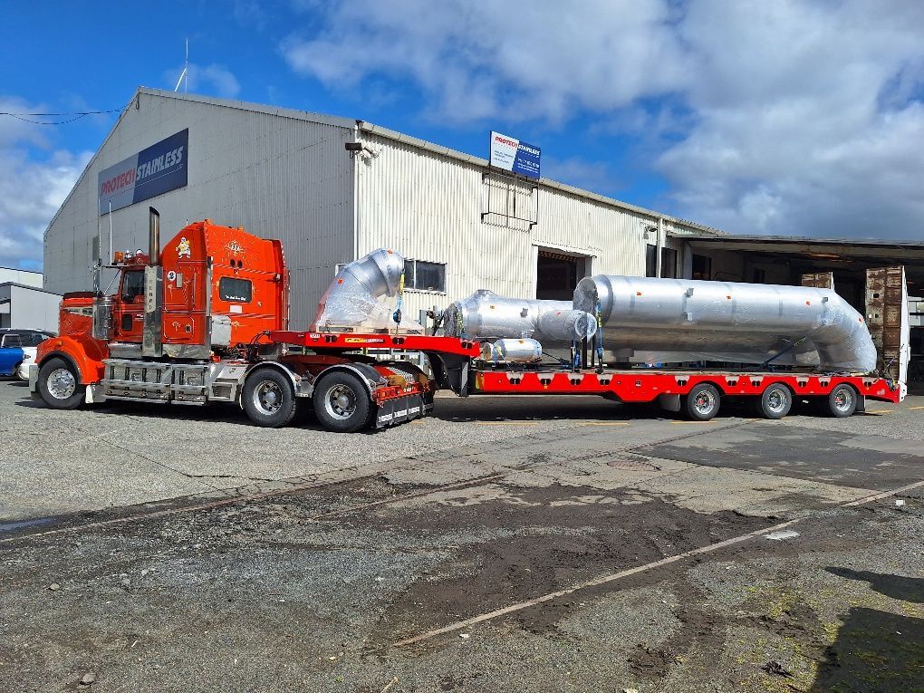 Industrial washer unit with safety warnings. Metal frame, mesh sides, internal spray nozzles, and conveyor. Industrial washer unit with safety warnings. Metal frame, mesh sides, internal spray nozzles, and conveyor.