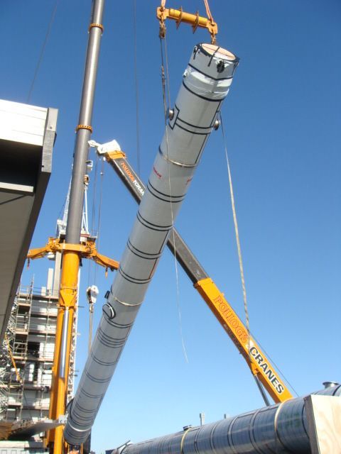 Workers assembling a large, spherical structure with a metal frame inside a warehouse.