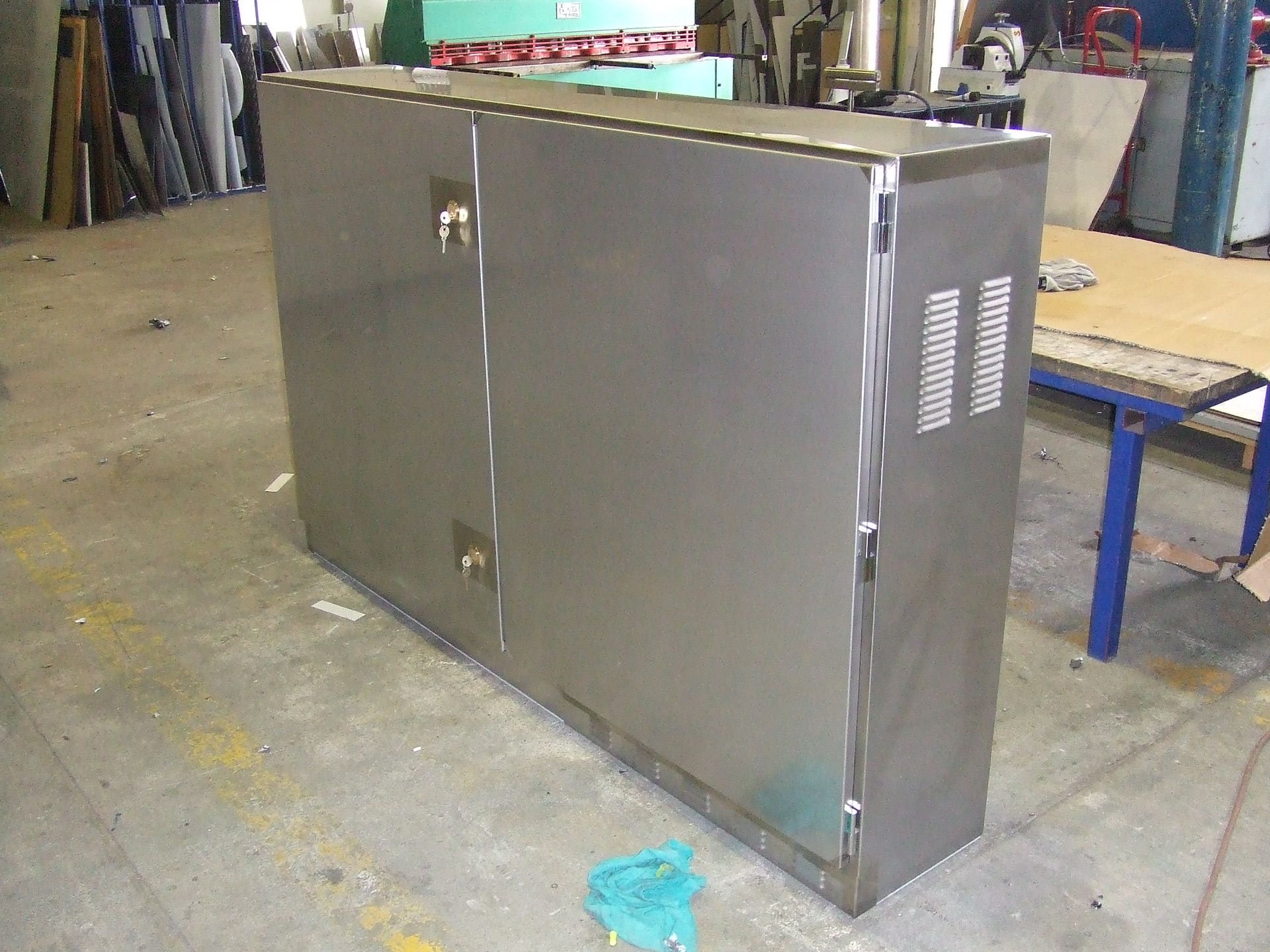 Stainless steel industrial processing tank with a funnel base in a workshop.