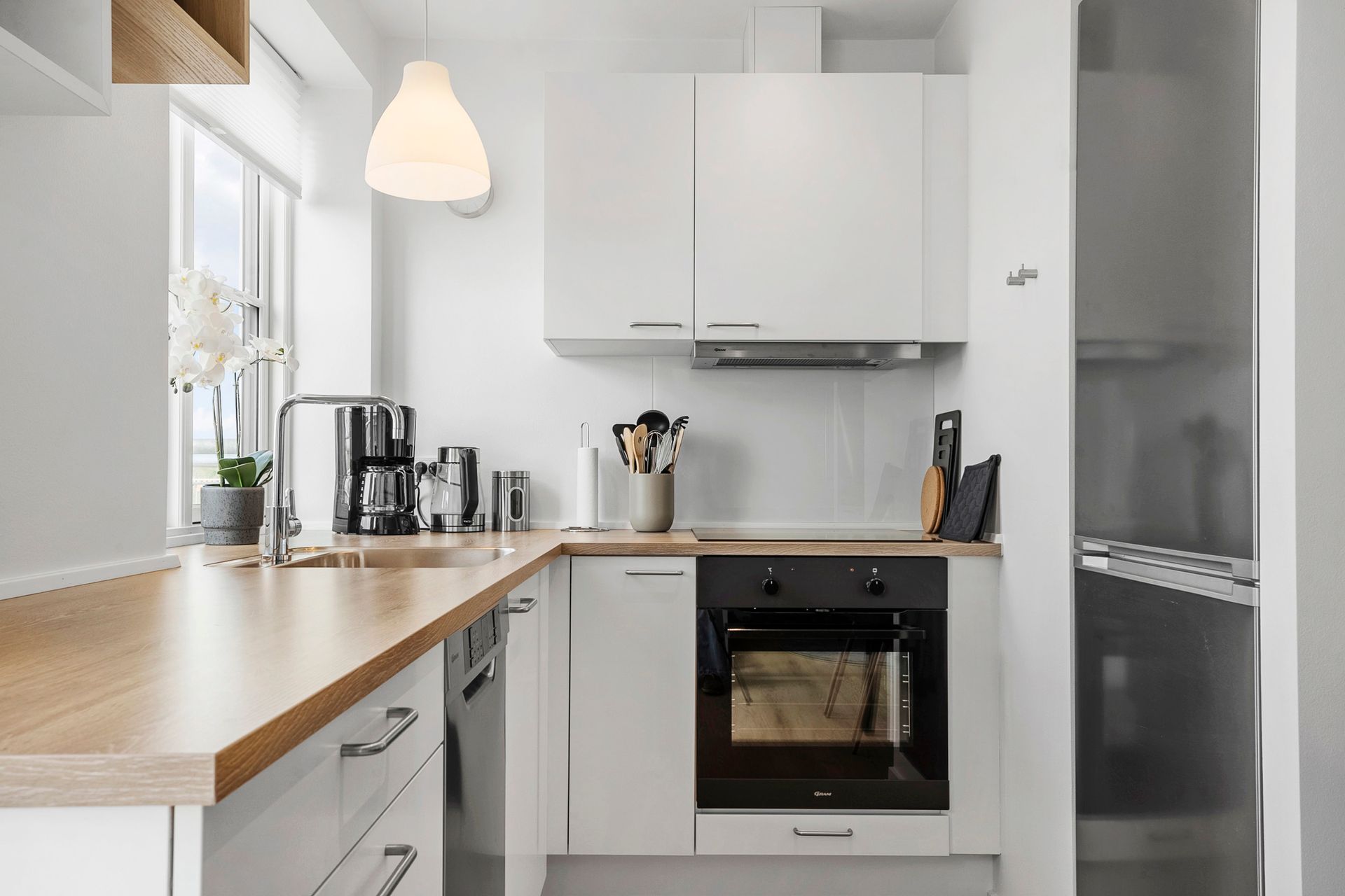 Hvidt køkken med træbordplader og indbygget ovn.