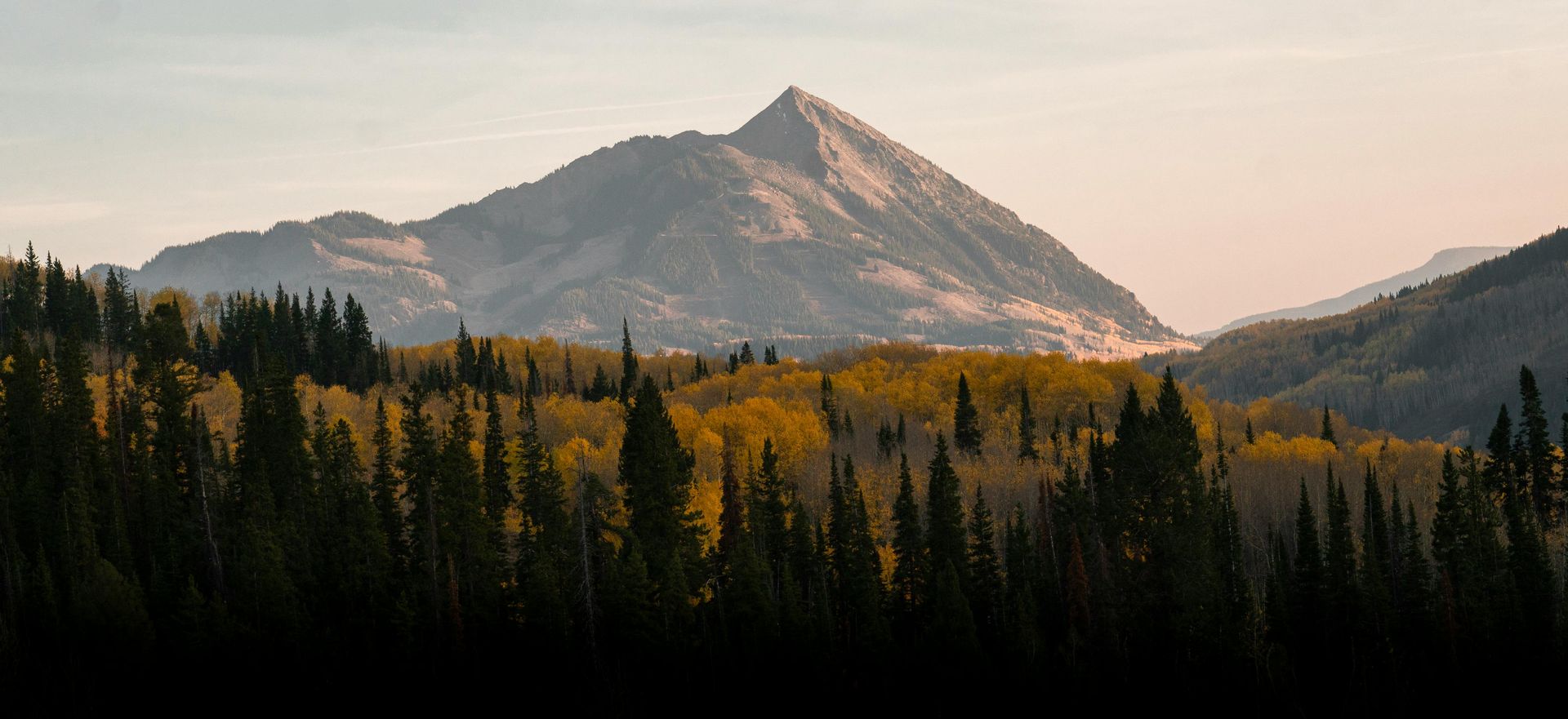 Mountain range at sunrise over forest.