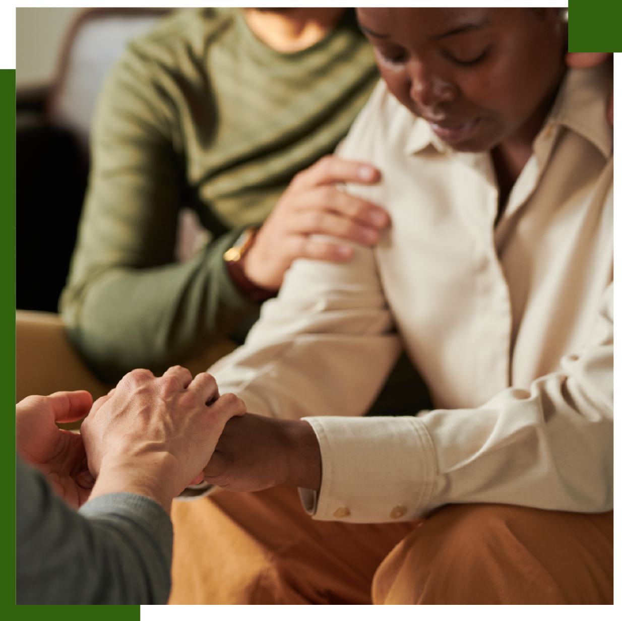 Hands holding and comforting a person; another person's hand on their shoulder.