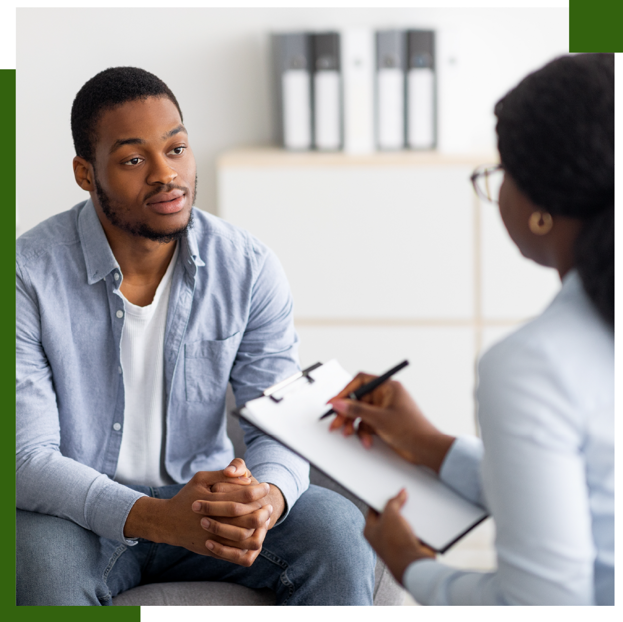Man in therapy session with therapist taking notes.