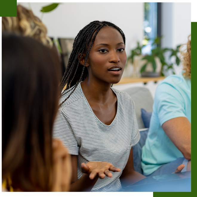Woman with long braids speaks in a group setting.