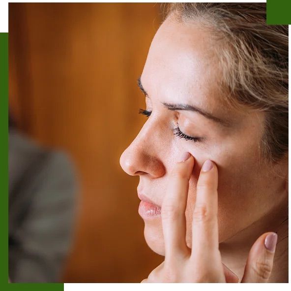 Woman touching under her eye, indoors, eyes closed.