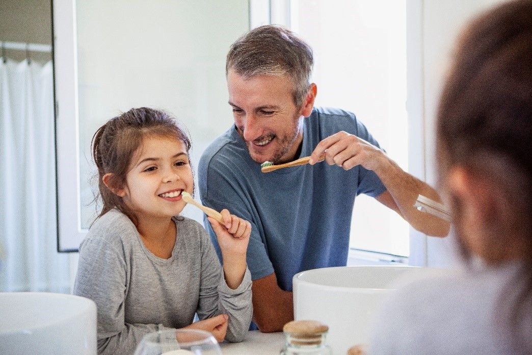 Kid brushing teeth with parent