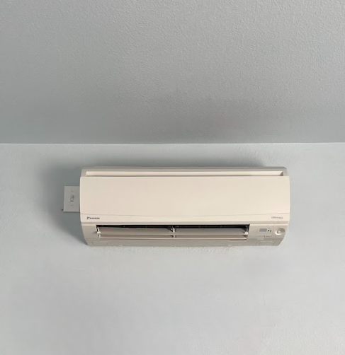 White air conditioner mounted on a light blue wall.