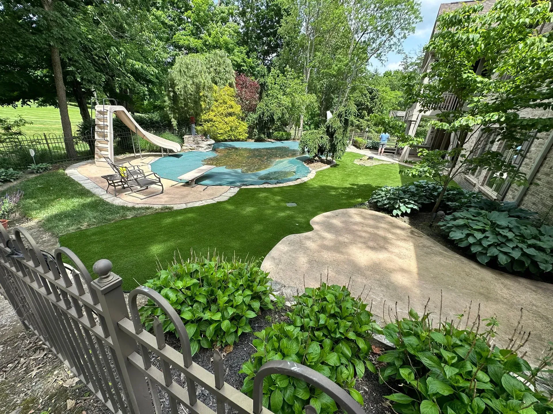 A large backyard with a swimming pool and a slide.