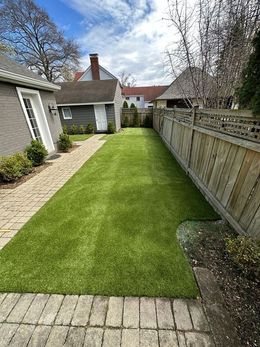 A long grassy path leading to a house with a wooden fence.