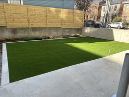 A backyard with a wooden fence and a lush green lawn.