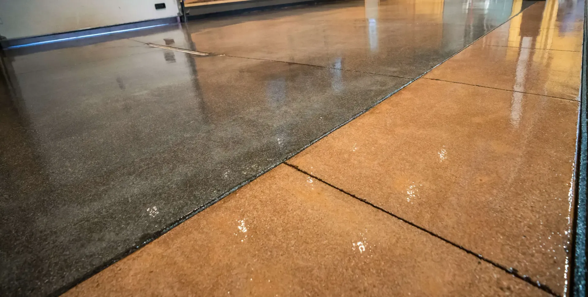 Polished concrete flooring with a distinct transition between a grey speckled section and a warm tan, tiled area.