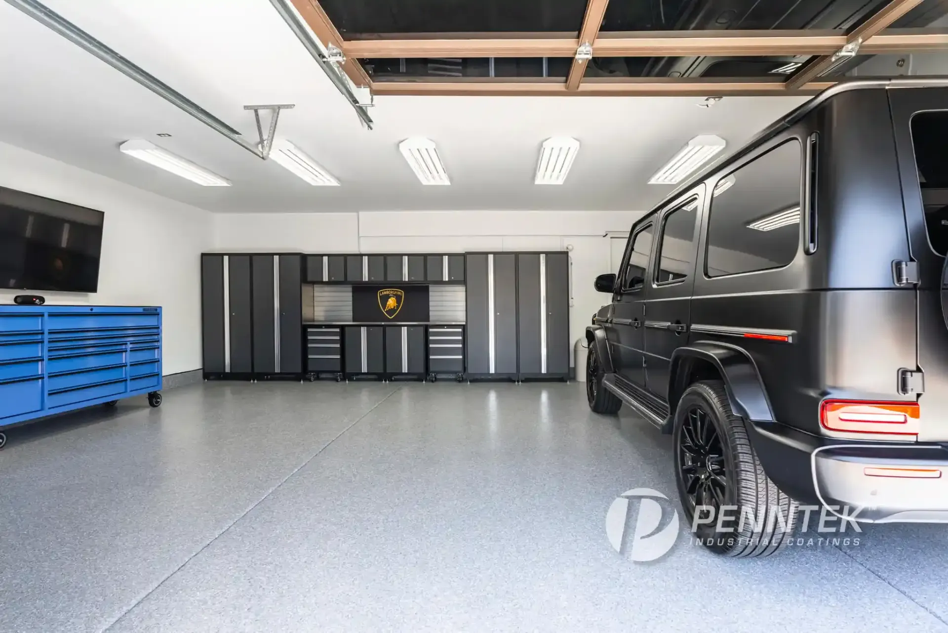 A modern garage with epoxy flooring, black metal cabinetry, overhead LED lighting, and a black SUV parked inside.