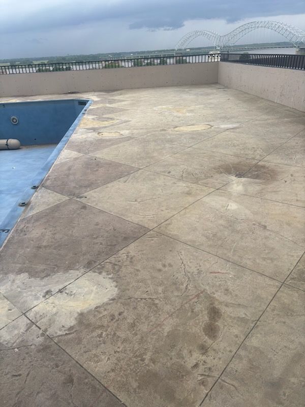 Empty rooftop terrace beside a blue pool, with a bridge in the distance.