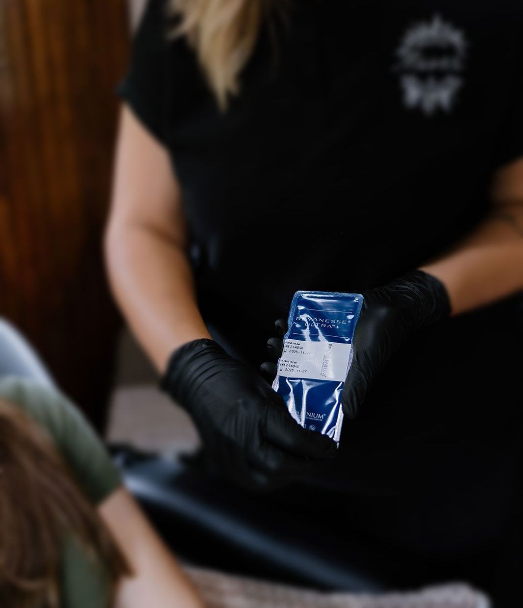 A woman wearing black gloves is holding a blue and white bag.