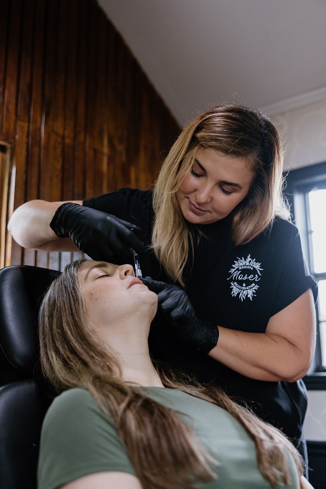 A woman is getting a tattoo on her face in a salon.