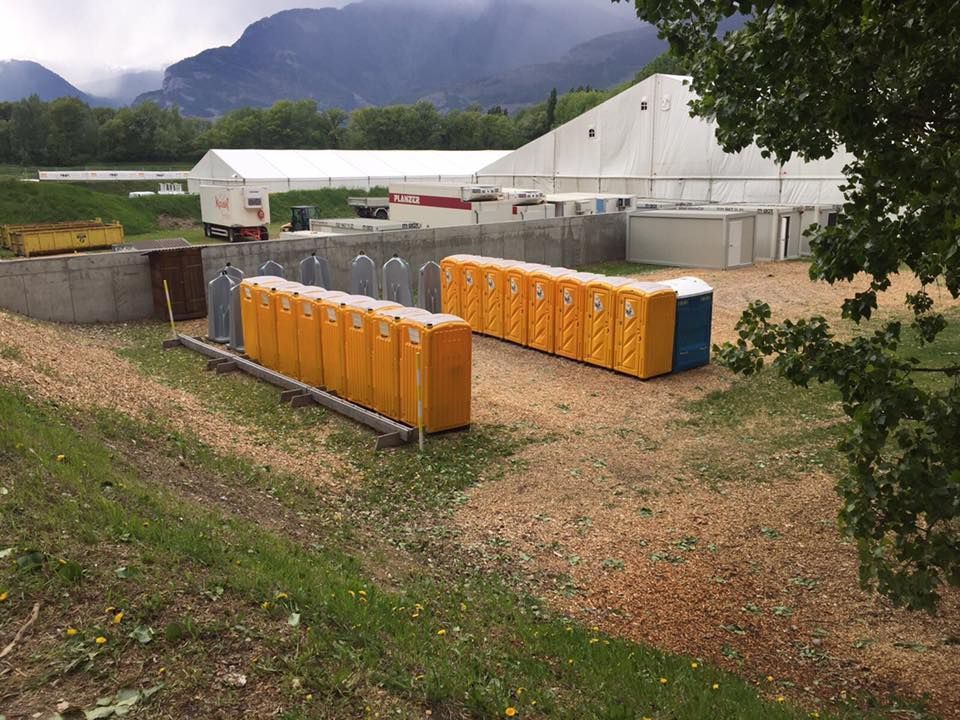 Une rangée de toilettes portables jaunes est alignée dans un champ.