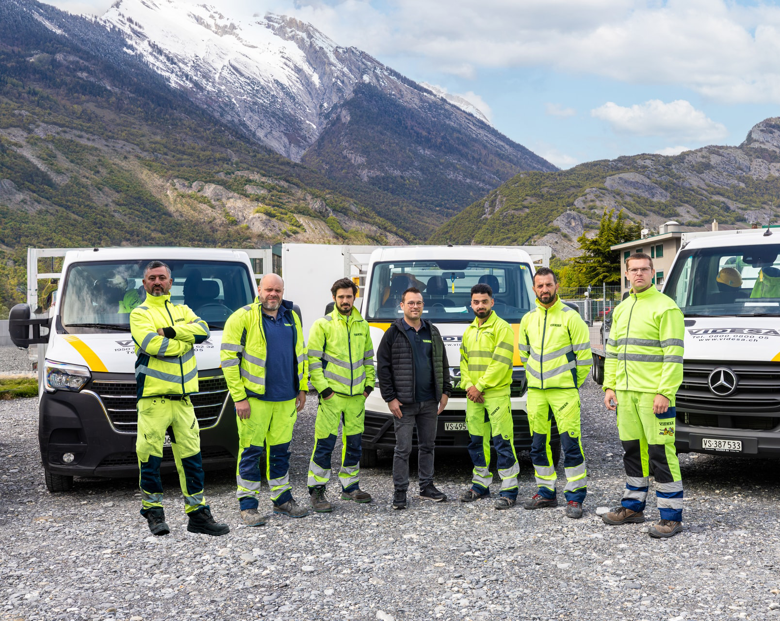 Un groupe d'hommes se tient devant une rangée de camionnettes.