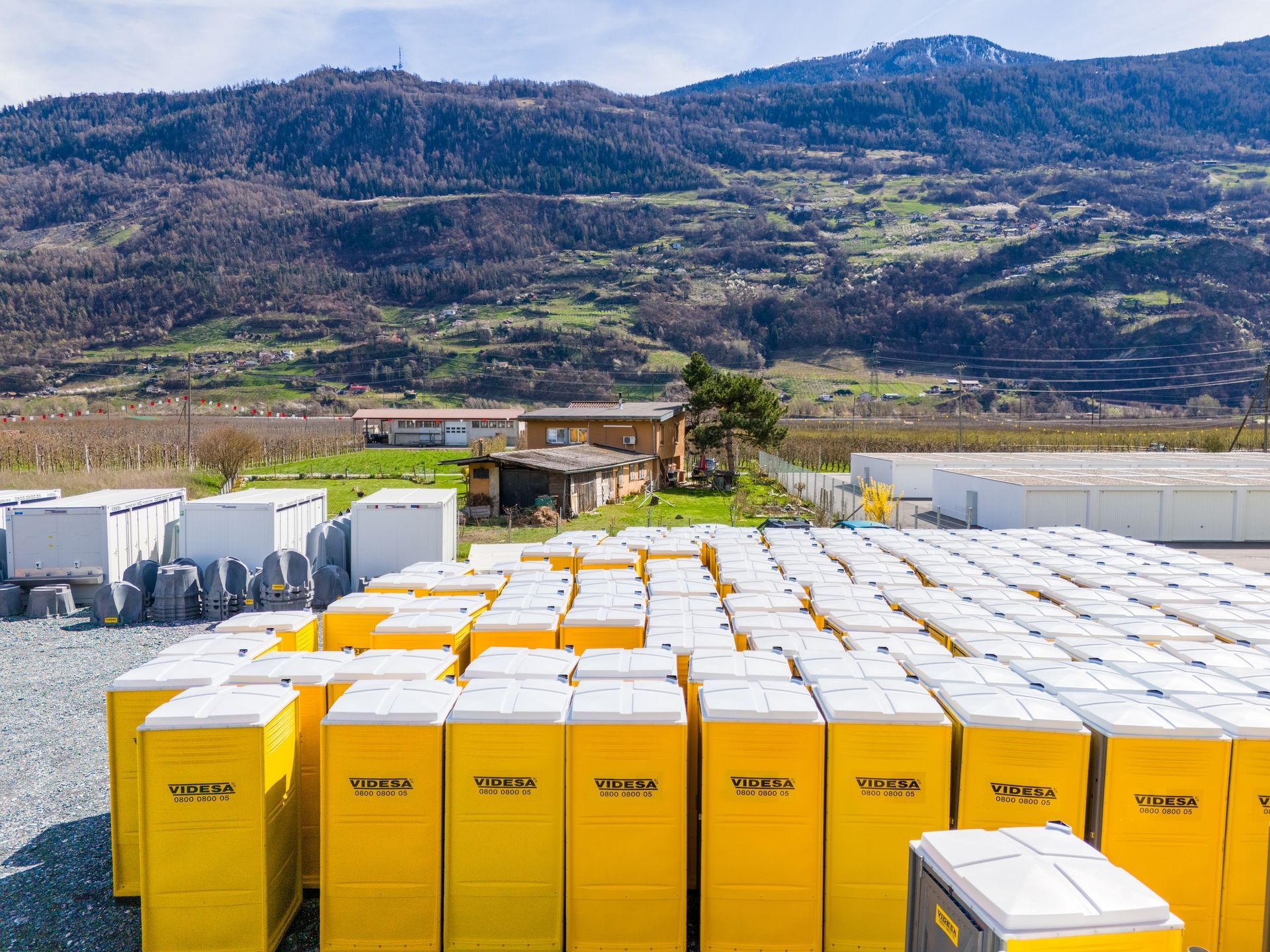 Une grande pile de conteneurs jaunes et blancs dans un champ avec des montagnes en arrière-plan.
