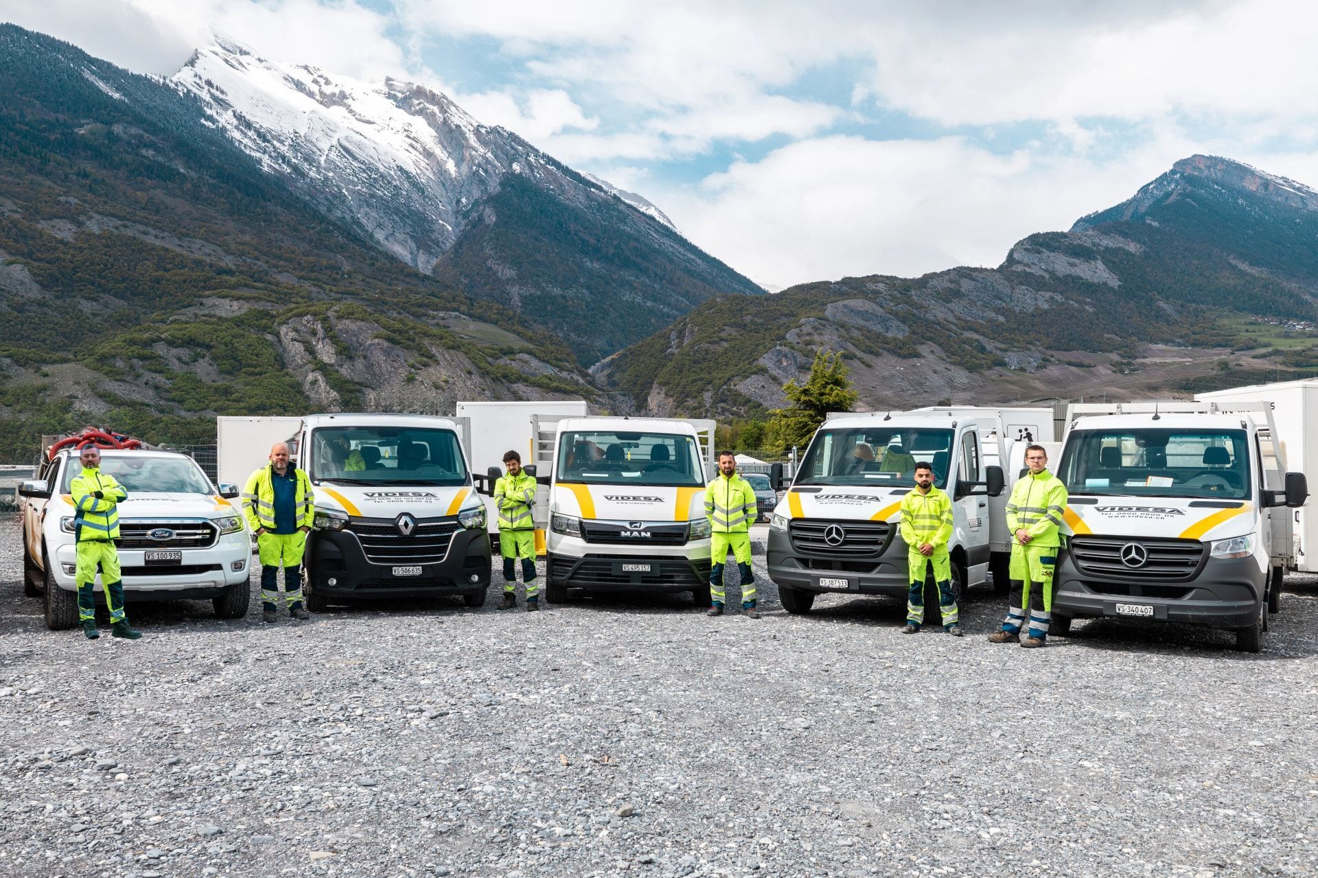 Un groupe de personnes debout devant une rangée de camionnettes.