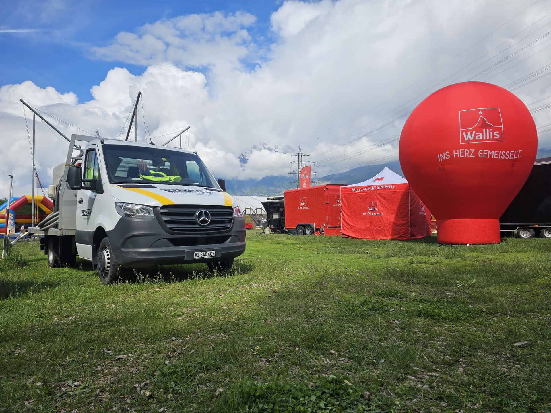 Une camionnette blanche est garée dans un champ herbeux à côté d'un ballon gonflable rouge.