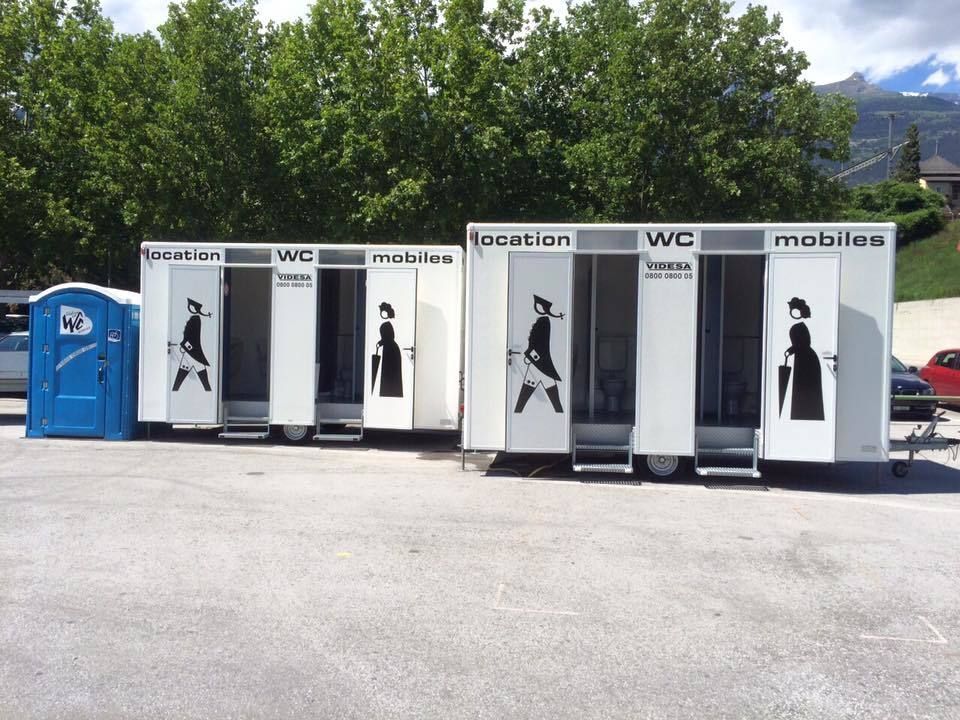 Une rangée de toilettes mobiles est garée sur un parking