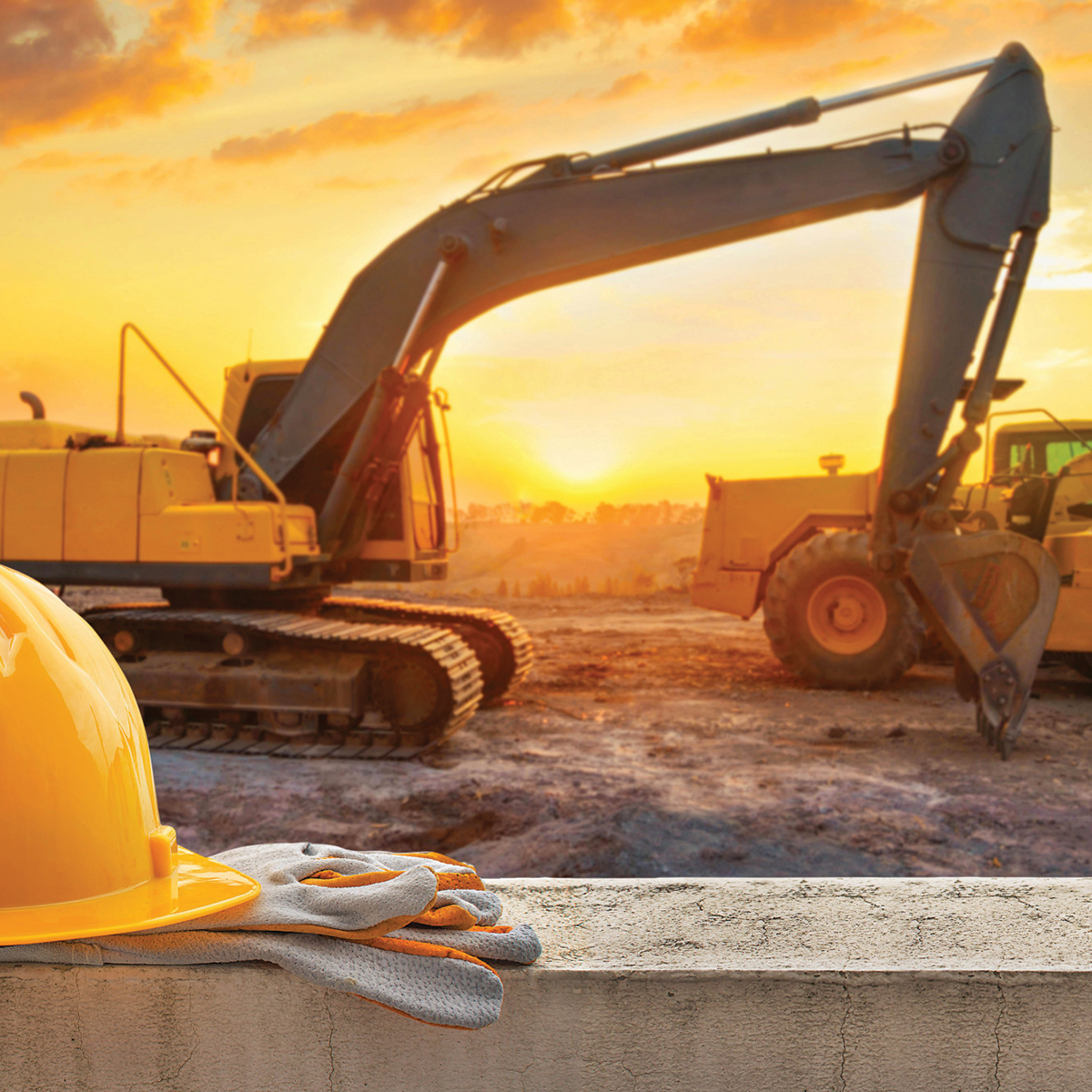 Un casque et des gants sont posés sur un mur devant un chantier de construction.
